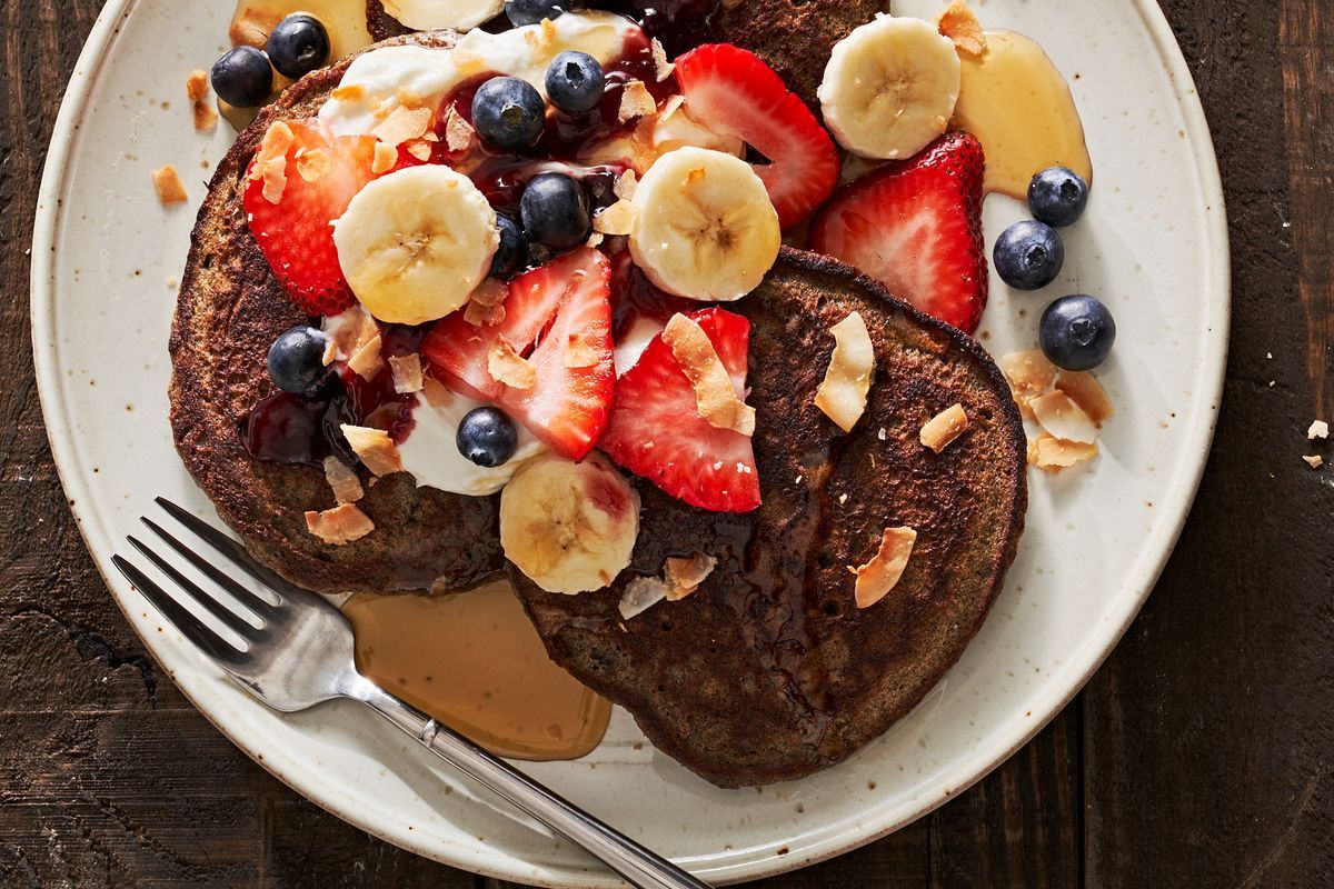 Mouth-watering Buckwheat Pancakes with fruits on a white plate with a fork.