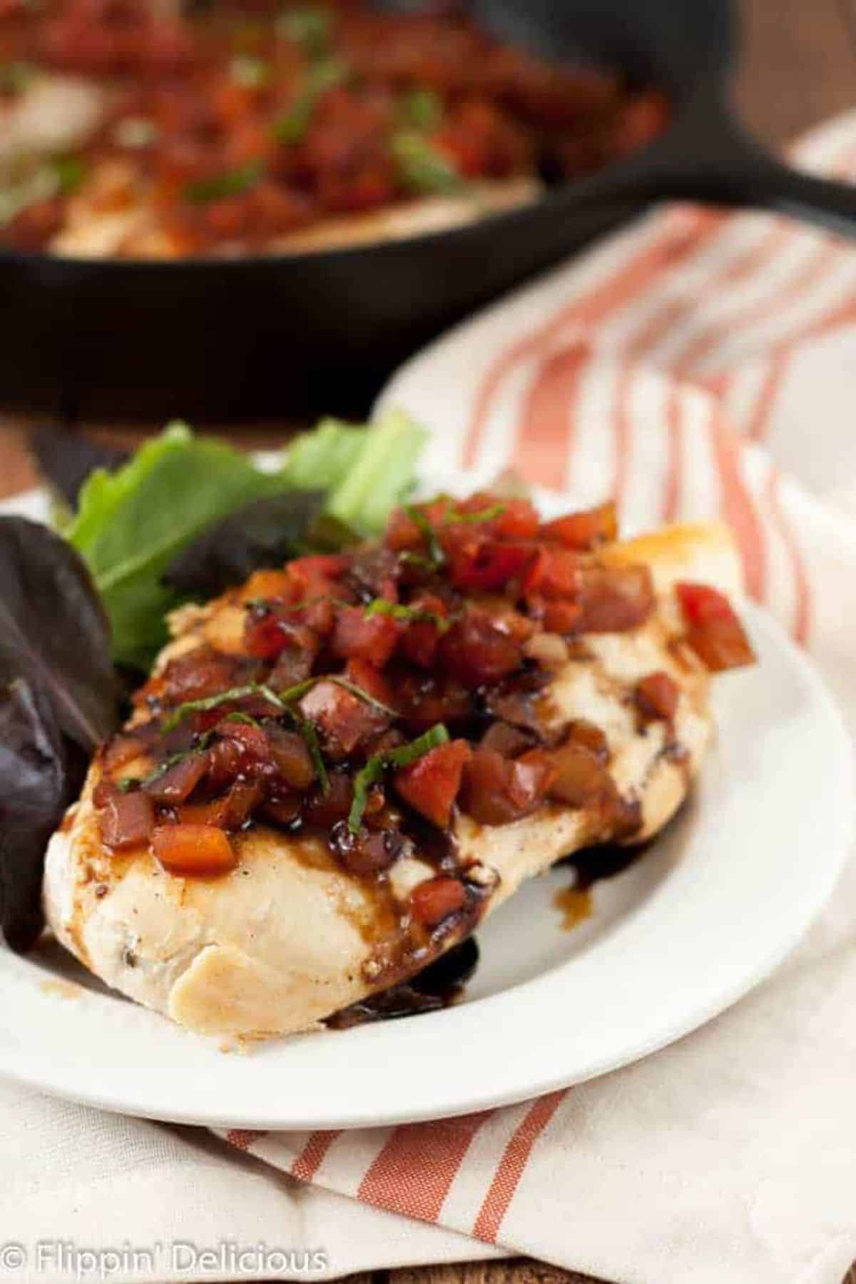 Mouth-watering Gluten-Free and Dairy-Free Bruschetta Chicken Skillet with salad on a white plate.