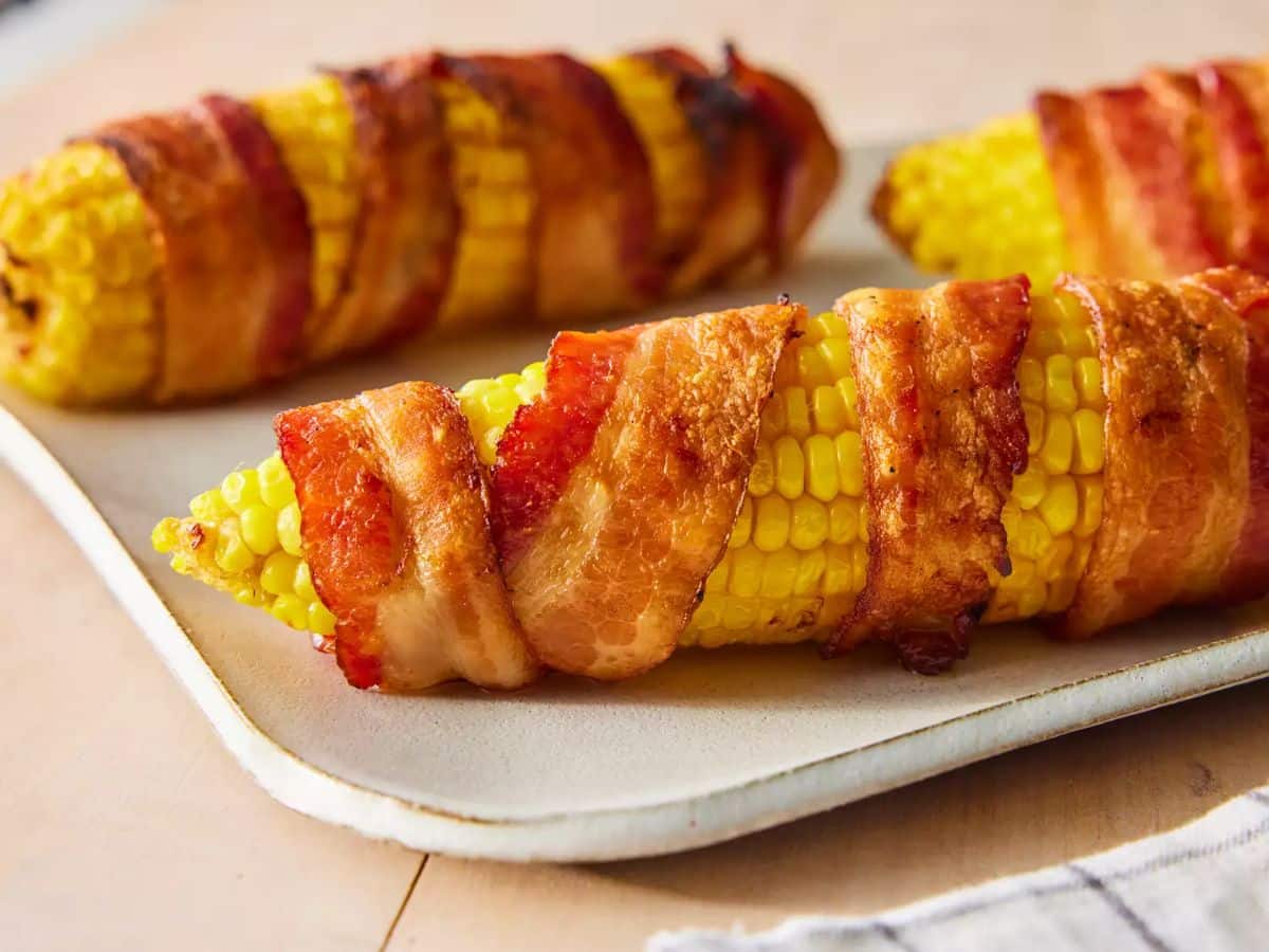 Tasty Grilled Bacon-Wrapped Corn on the Cobs on a tray.