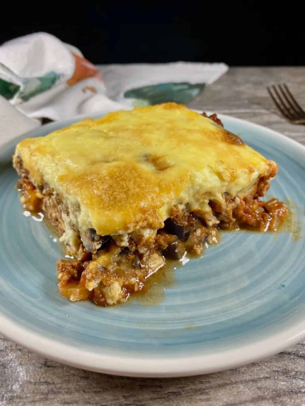 A piece of Gluten-Free Greek Moussaka on a blue plate.