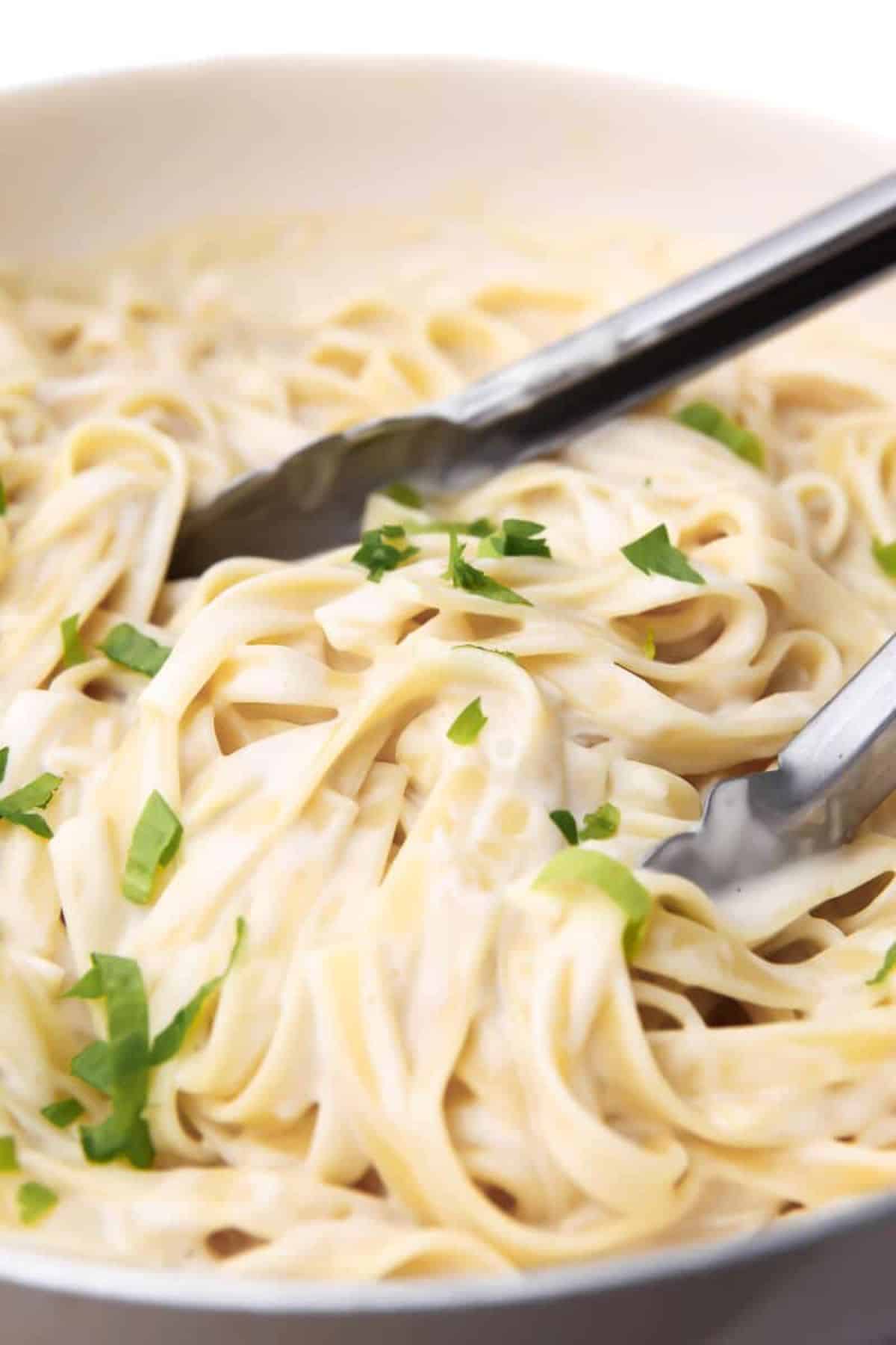 Deliicous pasta with Vegan Alfredo Sauce in a white bowl.