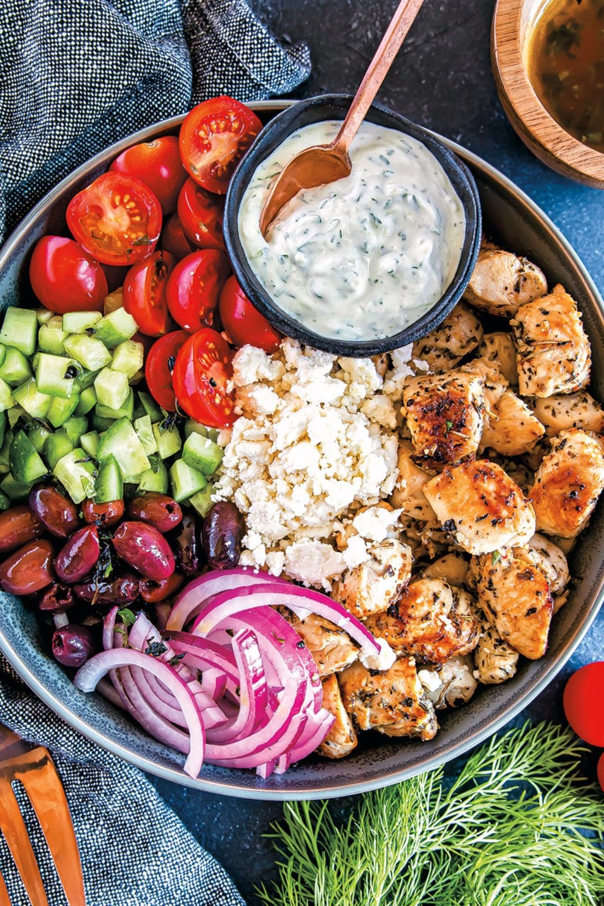 Scrumptious Low-Carb Greek Chicken with veggies and a bowl of dip on in a big bowl.