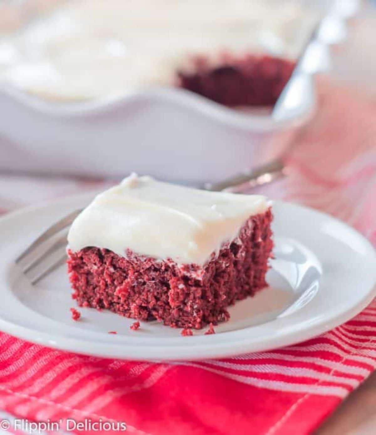 A piece of delicious Red Velvet Cake on a white plate with a fork.