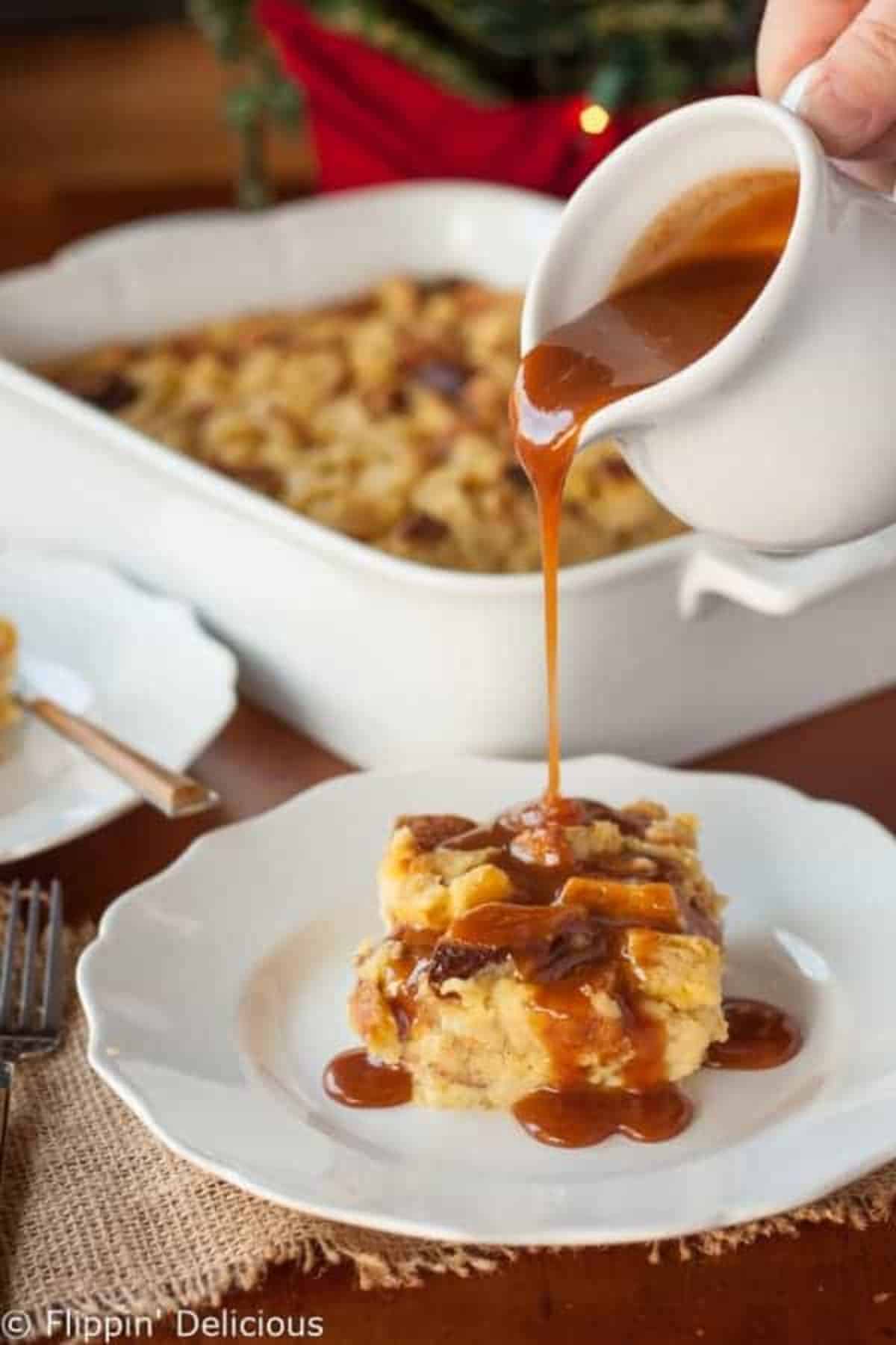 A piece of Gluten-Free Eggnog Bread on a white plate drizzled with syrup.