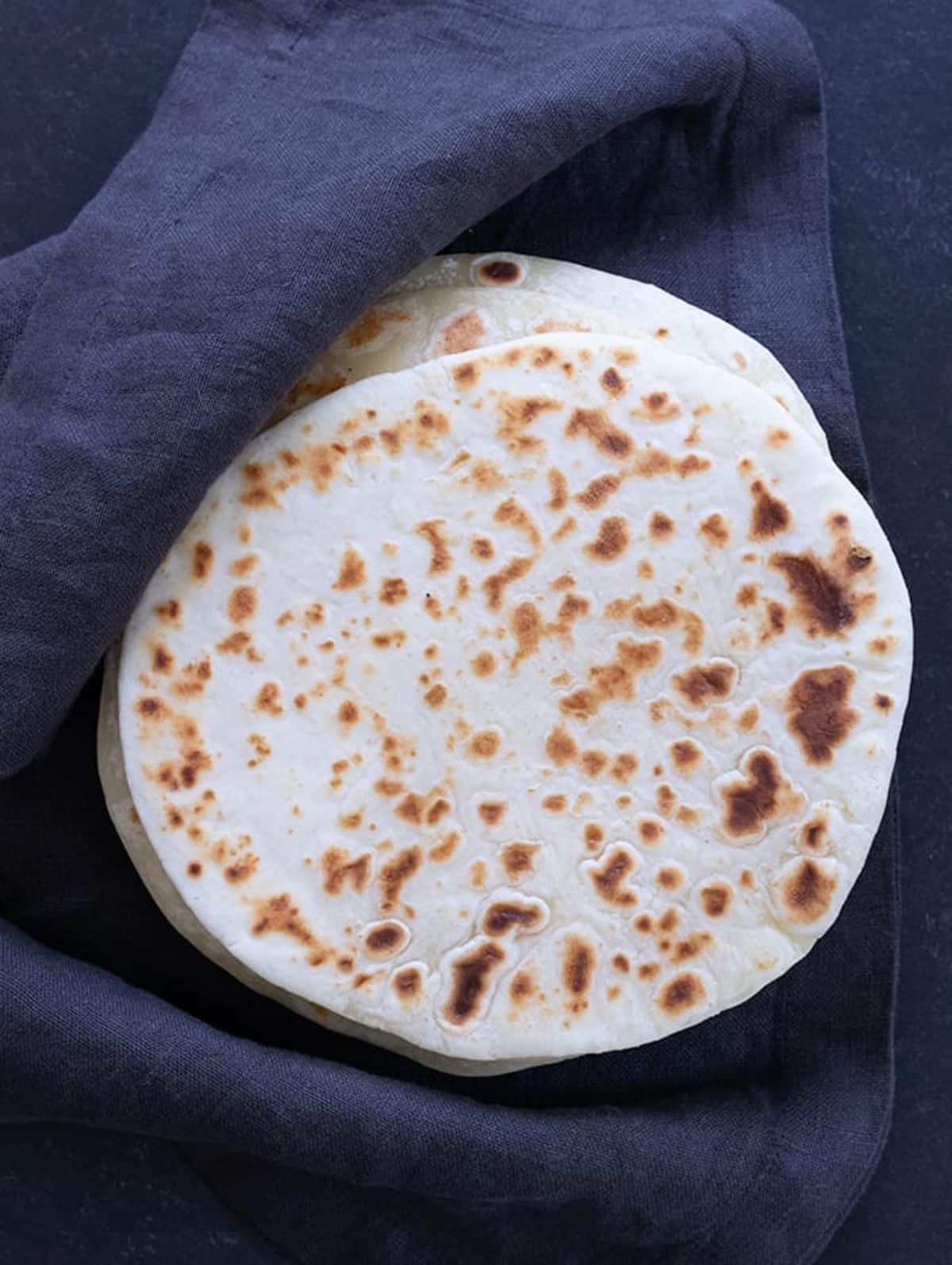 A pile of Gluten-Free Soft Tapioca Wraps on a blue tablecloth.