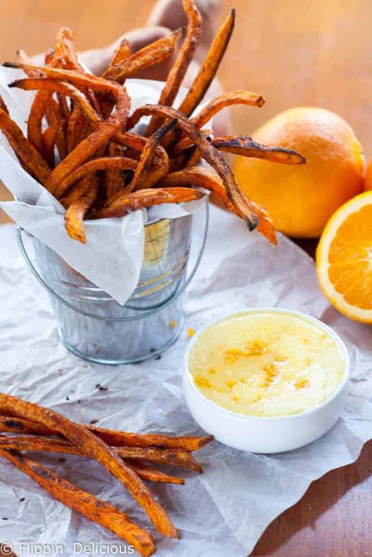 Crispy Baked Sweet Potato Fries with Orange Zest Icing Dipping Sauce on a table.