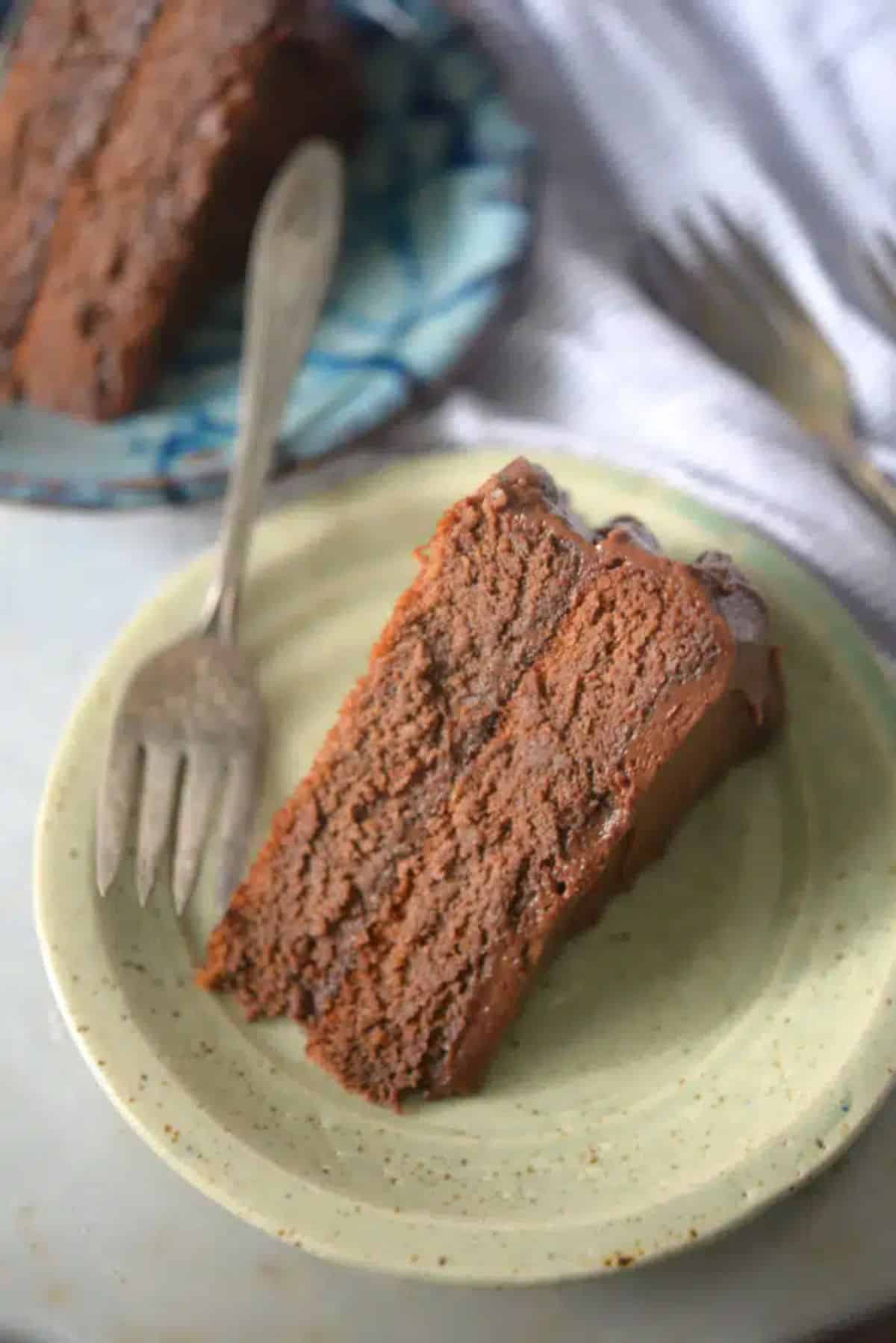 A piece of Coconut Flour Chocolate Cake on a green plate with a fork.