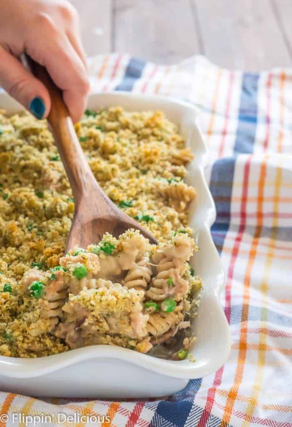 Delicious Gluten Free Tuna in a white casserole picked by a wooden spatula.